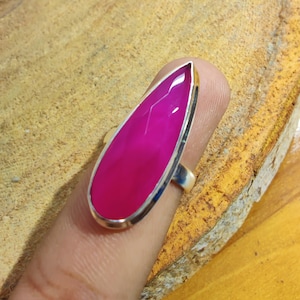 Op de afbeelding: Een zilveren ring met een druppelvormige roze edelsteen.