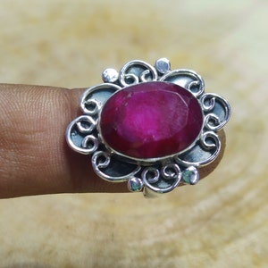 May include: A silver ring featuring a pink oval gemstone set within an ornate filigree design.