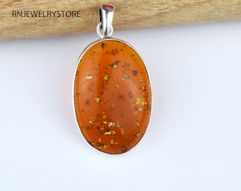 May include: Oval shaped amber pendant with gold flecks, set in silver.