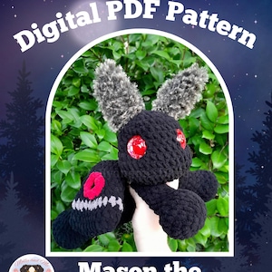 Puede incluir: Un peluche de ganchillo llamado Mason the Mothling, con un cuerpo negro difuso, dos grandes ojos rojos y orejas texturizadas grises y negras. Las alas son negras con detalles circulares rojos y costuras blancas. El texto dice Digital PDF Pattern.