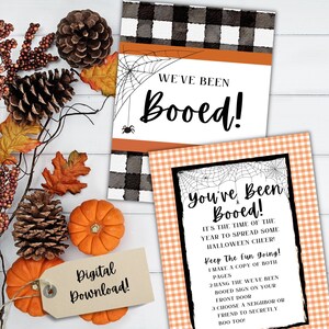 Könnte beinhalten: Zwei druckbare Halloween-Schilder "Booed!" mit einem schwarz-weiß karierten Hintergrund und orangefarbenen Akzenten. Der Text auf den Schildern lautet "We've Been Booed!" und "You've Been Booed!" mit Anweisungen, wie man das Spiel spielt.
