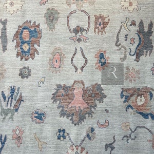 May include: A beige rug with a repeating pattern of stylized floral motifs in shades of blue, brown, and pink.