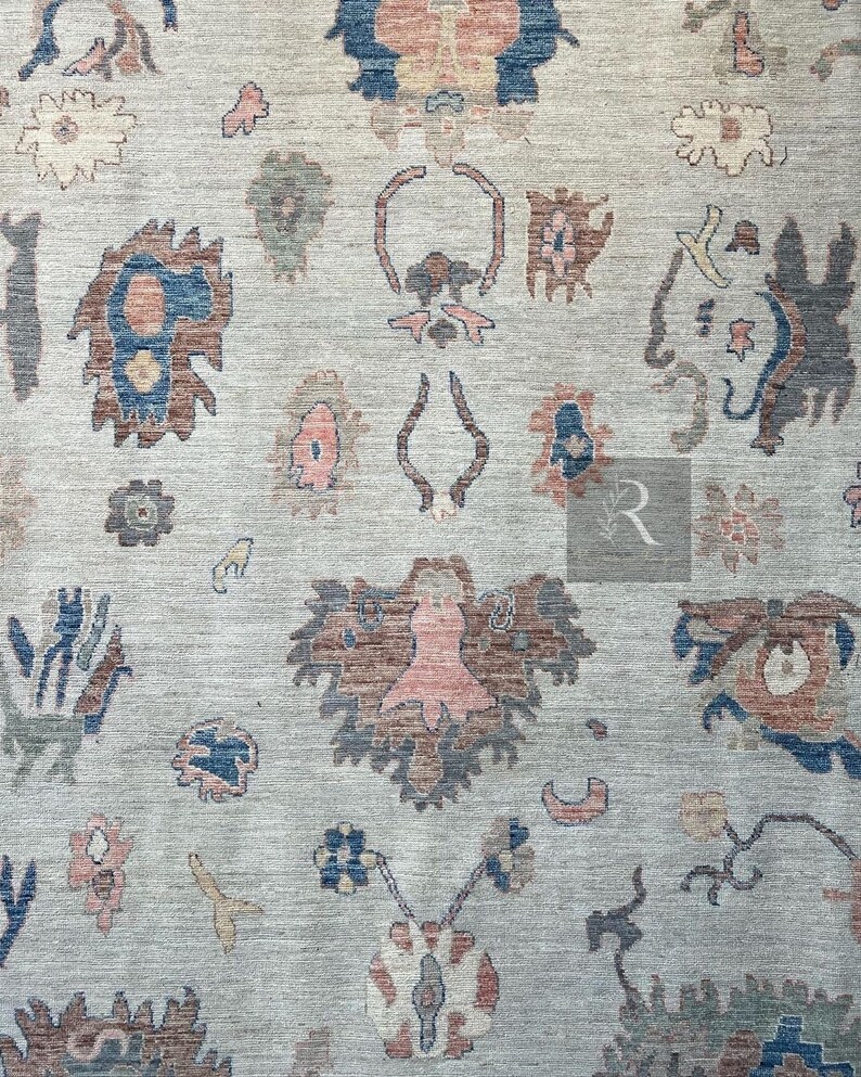 May include: A beige rug with a repeating pattern of stylized floral motifs in shades of blue, brown, and pink.