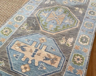 May include: A blue and beige patterned rug with intricate geometric designs. The rug has a light blue border with a subtle floral pattern.