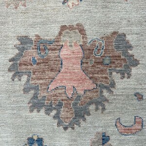 May include: A beige rug with a pink and blue floral pattern. The rug has a traditional design with intricate details.