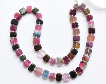 Könnte beinhalten: Eine Strähne aus mehrfarbigen quadratischen Edelsteinperlen. Die Perlen sind eine Mischung aus Rosa, Grün, Blau, Schwarz und Braun.