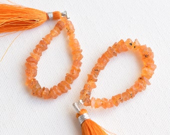 May include: Two orange gemstone bracelets with orange tassel charms. The bracelets are made of small, faceted, orange gemstones.