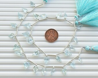 May include: A strand of light blue aquamarine gemstone beads with silver spacers and two light blue tassels. The beads are faceted and have a pointed shape. The strand is approximately the size of a US penny.