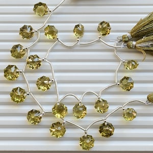 May include: A necklace featuring faceted, olive-green gemstones strung on silver-colored wire. The necklace is accented with two olive-green tassel pendants. The gemstones are arranged in a symmetrical pattern.