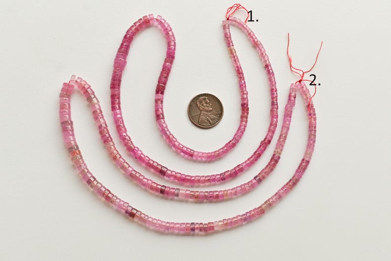 May include: Three strands of pink tourmaline beads, each strand is approximately 18 inches long. The beads are faceted and have a square shape. A US penny is included for size reference.