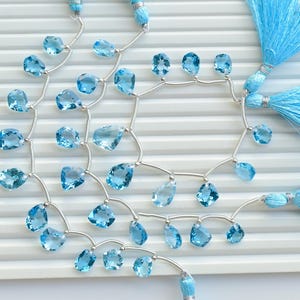 May include: A strand of light blue gemstone beads with silver connectors and blue tassel accents.