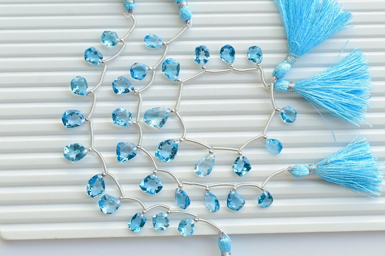 May include: A strand of light blue gemstone beads with silver connectors and blue tassel accents.