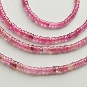 May include: Three strands of pink gemstone beads, each strand is made of small square-shaped beads.