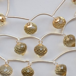 May include: A gold and silver necklace with multiple strands of beads and dangling faceted citrine stones.
