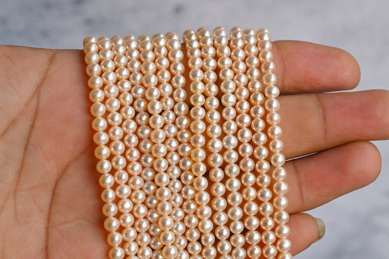 May include: A strand of cream-colored pearl beads, arranged in rows, with a smooth, glossy finish.