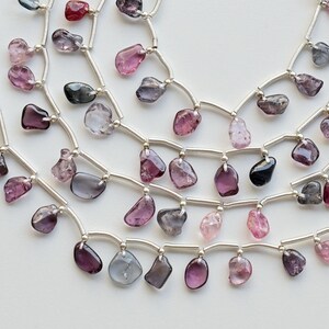 May include: A strand of silver chain with multiple rows of dangling, faceted, gemstone beads in shades of pink, purple, and gray.
