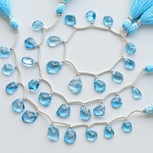 May include: A strand of light blue gemstone beads with silver connectors and tassels. The beads are faceted and have a teardrop shape.