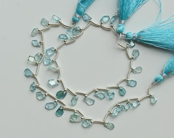 May include: Strands of light blue gemstone beads with silver accents and matching turquoise tassels. The beads are irregularly shaped and strung on a silver wire. The tassels are made of fine, silky threads.