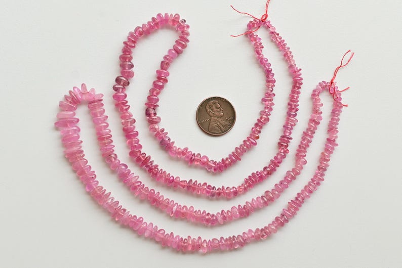 May include: Four strands of pink tourmaline beads, each strand is a different length. The beads are faceted and have a slightly irregular shape. The beads are strung on a thin thread and are ready to be used for jewelry making.
