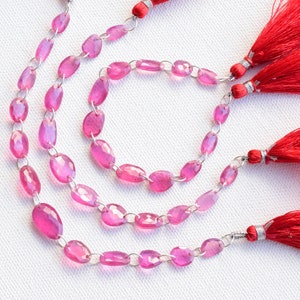 May include: Three strands of pink oval gemstone beads with silver connectors and red tassel accents.