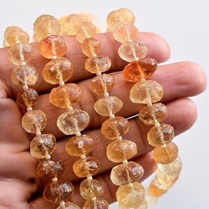 May include: A strand of faceted, translucent, golden-amber beads. The beads are irregular in shape and have a slightly rough texture. The beads are strung on a clear thread.