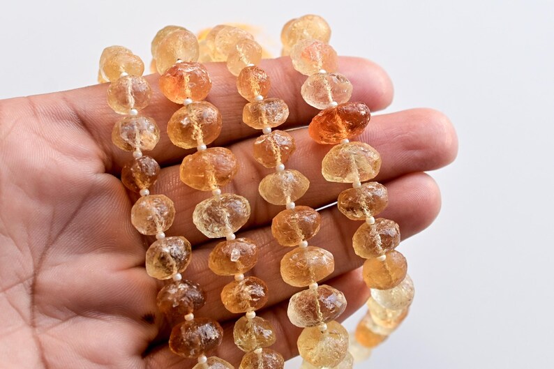 May include: A strand of faceted, translucent, golden-amber beads. The beads are irregular in shape and have a slightly rough texture. The beads are strung on a clear thread.
