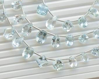 May include: A strand of light blue aquamarine gemstone beads. The beads are faceted and have a pear shape and a square shape. The beads are strung on a silver wire.