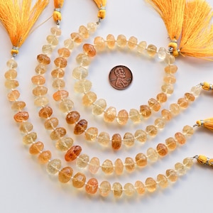 May include: A strand of light yellow to amber colored gemstone beads. The beads are faceted and have a slightly irregular shape. The strand is approximately 18 inches long and is strung on a silver wire. The beads are separated by small silver spacers. The strand is finished with a silver clasp and a yellow tassel.