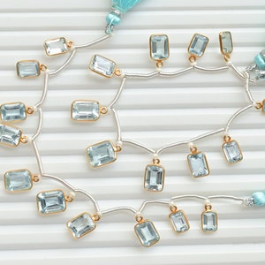 Puede incluir: Un collar de cadena de plata con colgantes de piedras preciosas azul claro. El collar tiene dos borlas azules en cada extremo.