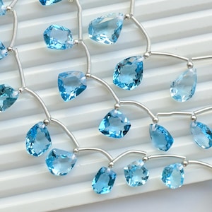 May include: A strand of light blue gemstone beads on a silver chain. The beads are faceted and have a teardrop shape. The chain is made of small silver beads.