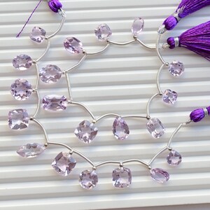 May include: A strand of pale pink amethyst gemstone beads strung on silver wire with purple tassels at each end.