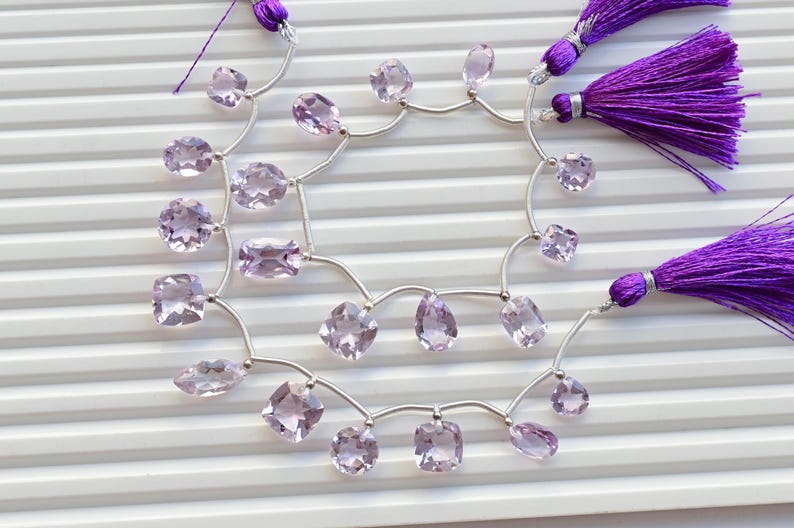 May include: A strand of pale pink amethyst gemstone beads strung on silver wire with purple tassels at each end.