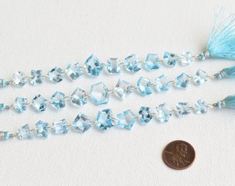 May include: Three strands of light blue topaz gemstone beads strung on silver wire with blue tassels at each end. A US penny is included for scale.