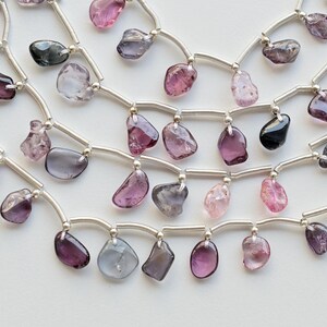 May include: A multi-strand necklace with silver chain and various shades of pink, purple, and gray gemstone beads.