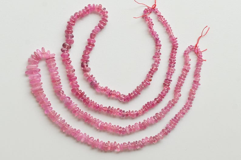 May include: Three strands of pink tourmaline gemstone beads. The beads are faceted and have a slightly irregular shape. The strands are of varying lengths.