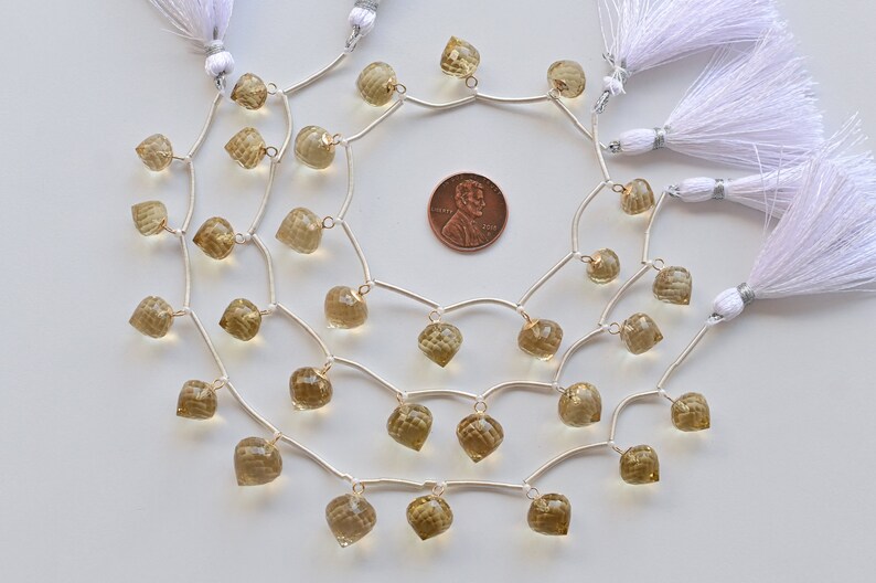 May include: A strand of light brown gemstone beads with silver jump rings and tassels. The beads are faceted and have a teardrop shape. The strand is approximately 18 inches long.