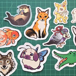 Adesivi di animali: lontra, pesce rosso, volpe, lupo, coniglietto farfalla, panino rosa, cervo colibrì, piccione viaggiatore, alligatore delle grandi sfide, pianto