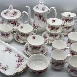 May include: A white tea set with floral designs. The set includes a teapot, creamer, sugar bowl, and six teacups and saucers.