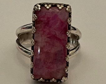 May include: A silver ring with a pink and white rectangular stone set in a decorative silver frame.