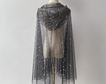 May include: A black sheer cape with a hood, covered in silver glitter. The cape is draped over a mannequin.
