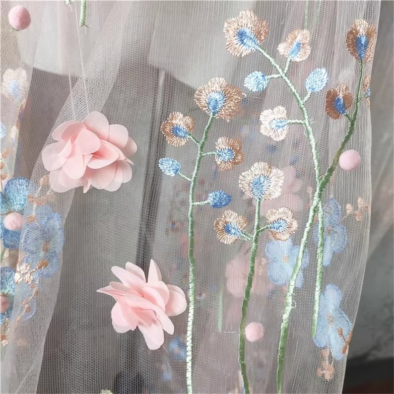 May include: Pink and blue floral embroidery on a sheer white fabric. The flowers are 3D and have a delicate texture.