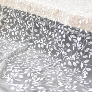 May include: White sheer fabric with an embroidered leaf pattern.