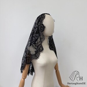 Peut inclure: Voile en dentelle noire avec un motif floral et des bords festonn&eacute;s. Le voile est drap&eacute; sur un mannequin, mettant en valeur son design d&eacute;licat et sa texture. Un accessoire traditionnel souvent utilis&eacute; pour les c&eacute;r&eacute;monies religieuses ou les occasions sp&eacute;ciales.
