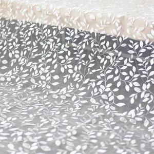 May include: White sheer fabric with an embroidered leaf pattern. The fabric is delicate and has a soft, flowing texture.