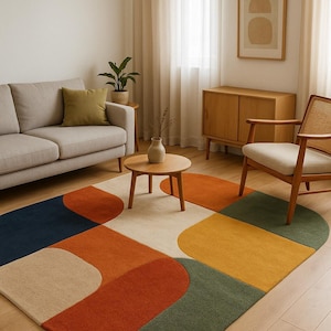 Può includere: Un tappeto colorato con un design geometrico. Il tappeto presenta una combinazione di forme e colori, tra cui blu navy, arancione, beige, giallo e verde. Il tappeto è collocato in un soggiorno con un divano, una sedia e mobili in legno.