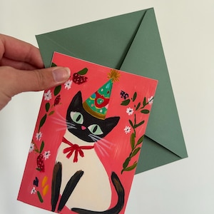 Carte anniversaire chat noir A6 – illustration festive avec chapeau, ruban rouge et fleurs – papeterie mignonne et colorée