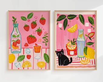 May include: Two framed art prints with a pink background. One features strawberries, lemons, and a bottle of beverage. The other print shows a black cat, lemons, and a beverage. Both prints have a light wood frame.