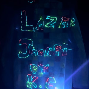 May include: A white jacket with the words "Lazer Jacket by K.C." written in neon green, pink, and blue.