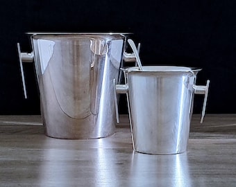 May include: Two silver ice buckets with handles. The larger bucket is taller and wider than the smaller bucket.