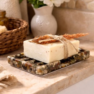 May include: A white ceramic mug with a black handle and the text "But First, Coffee" in a bold, black font. The mug is filled with a dark liquid, likely coffee, and sits on a light-colored surface.